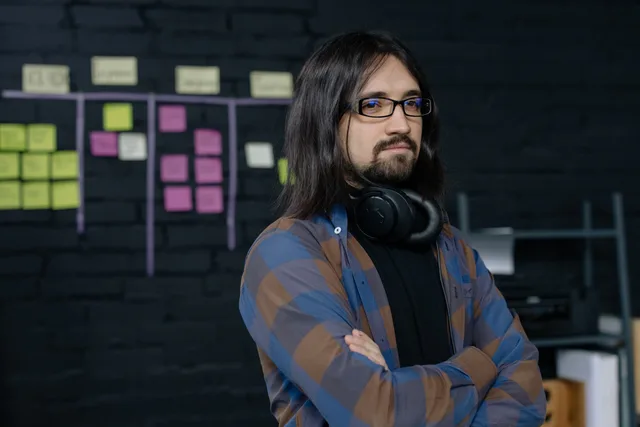 Portrait of a confident IT professional with headphones, standing in a modern office with sticky notes. Project software implementation